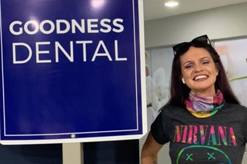 Girl standing next to Goodness Dental sign